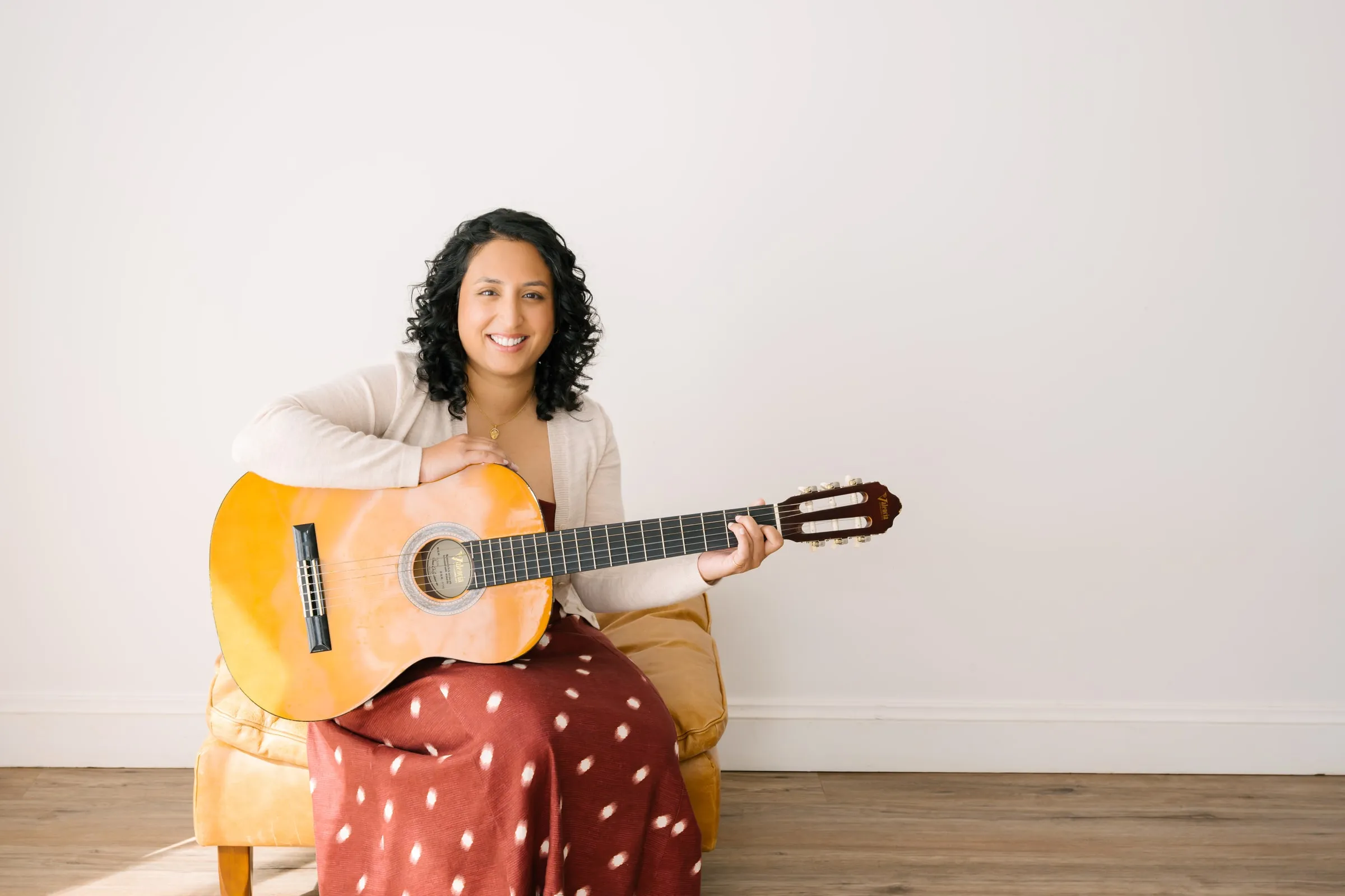 Maria John, Registered Music Therapist, smiling with her guitar