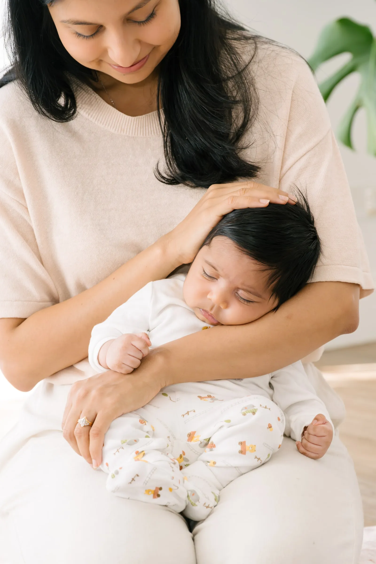 A mum cuddling her sleeping baby during a Mums and Bubs session