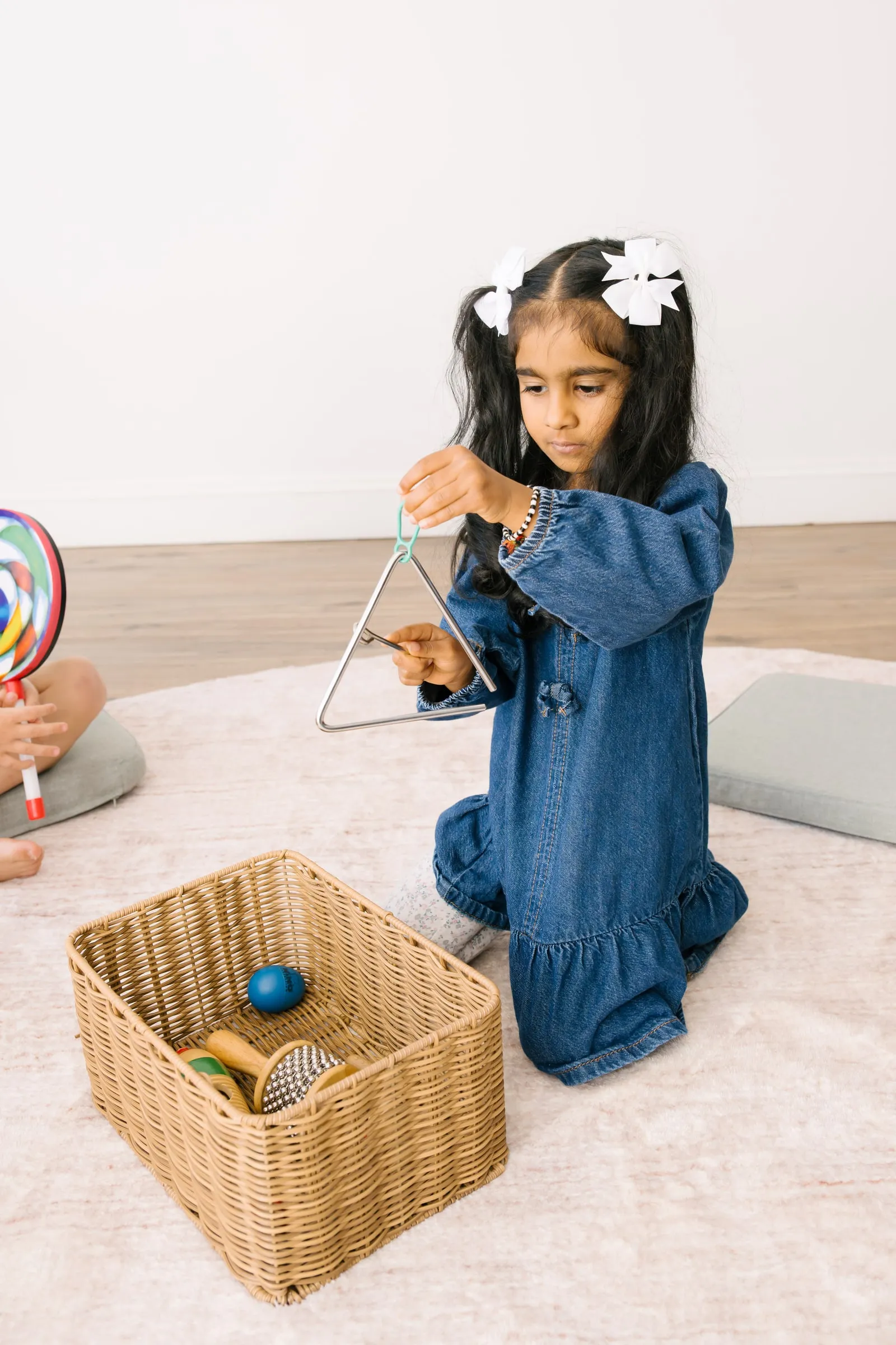 A girl playing a triangle during a preschool music group