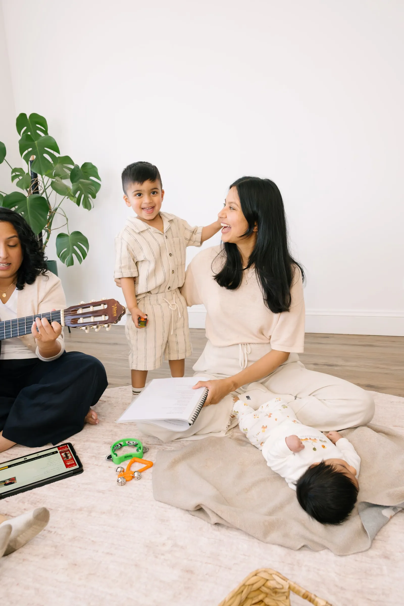 Maria smiling with young children and a baby during the mothers' singing group