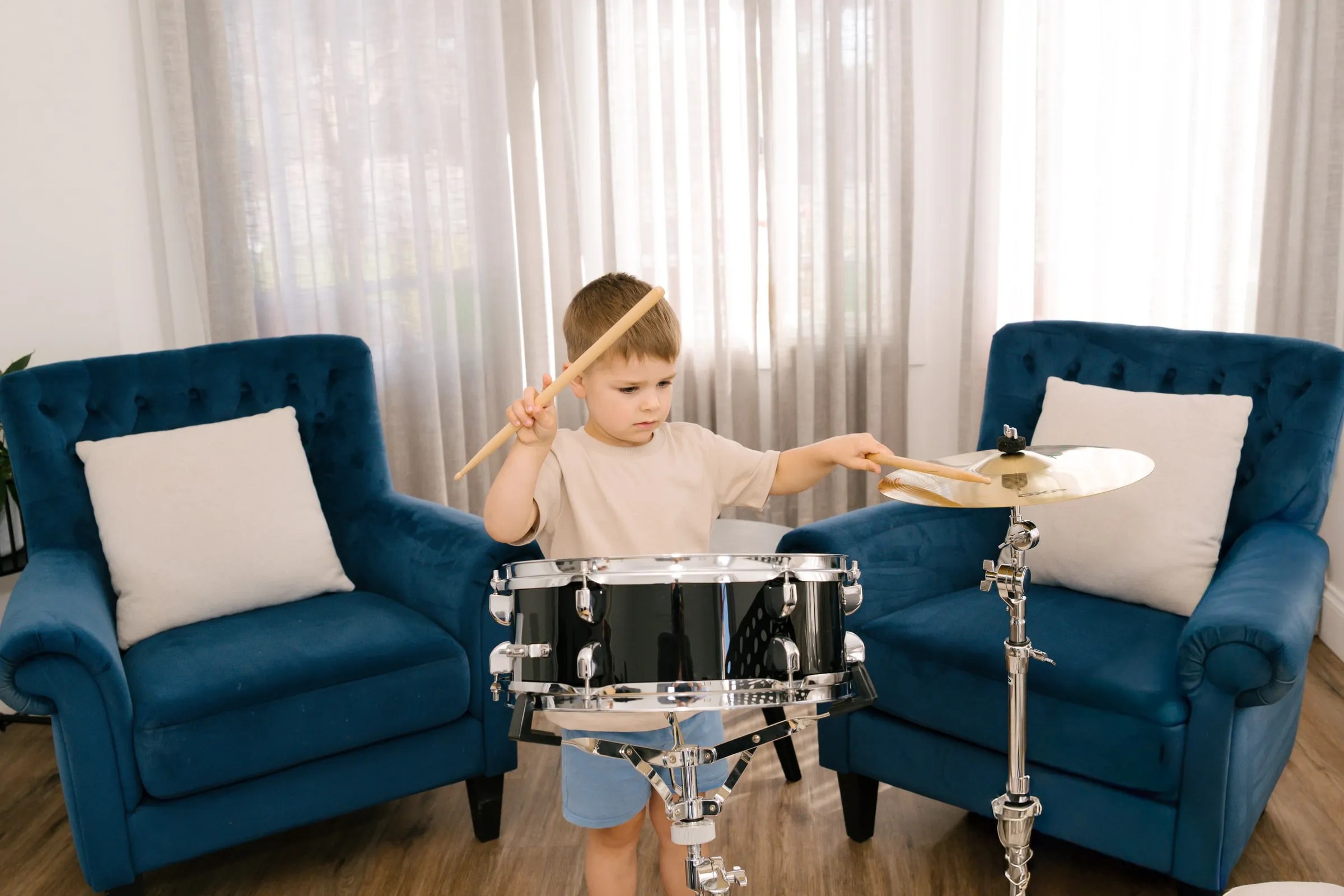 A boy playing a drum kit in his living room