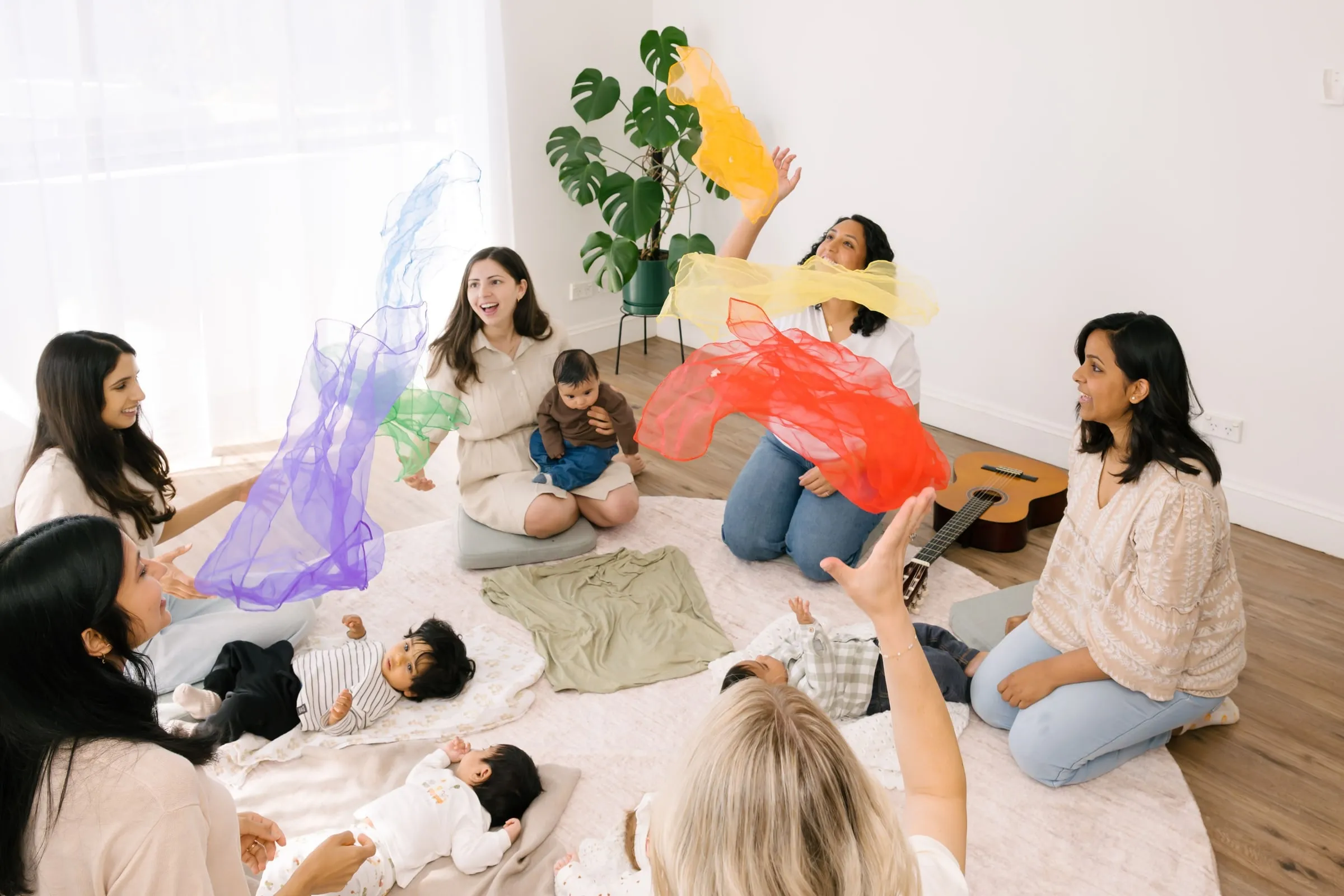 Mums and babies waving colourful scarves in a circle