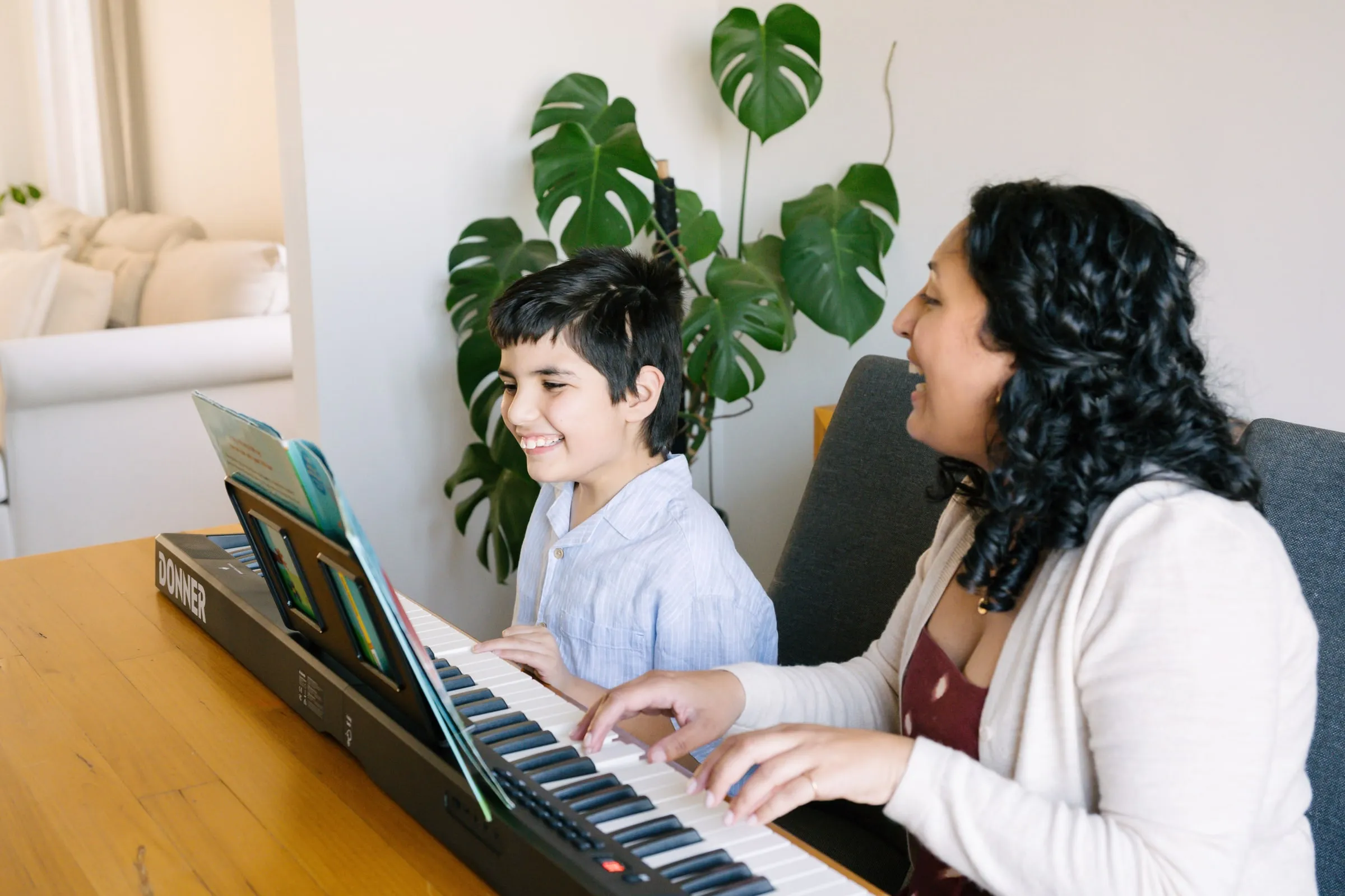 Maria and a young boy laughing together at the keyboard