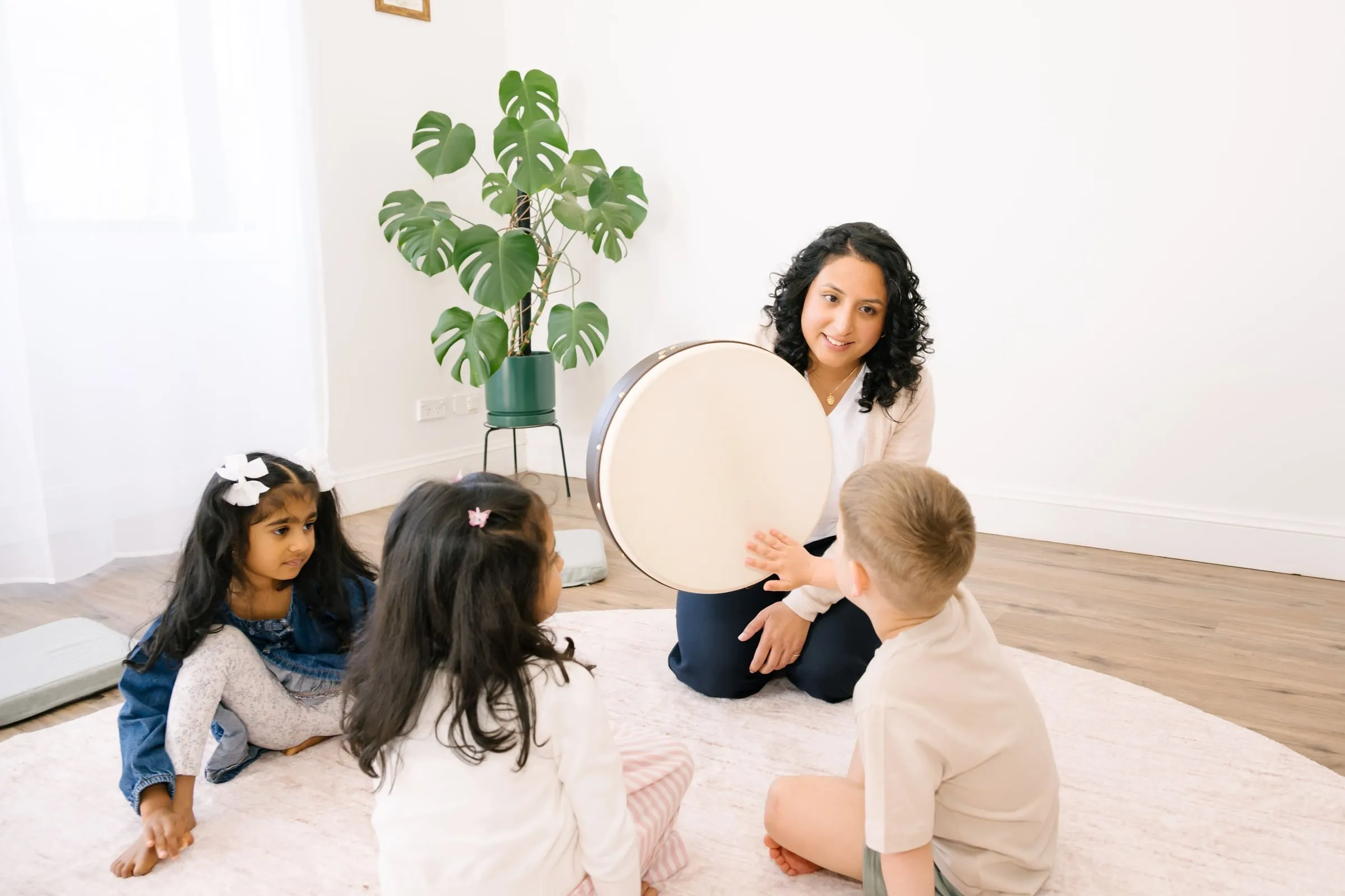 Preschoolers gathered around a large frame drum